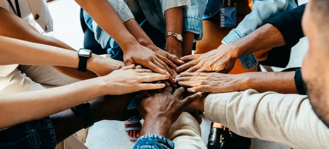 A team joining hands together in a circle